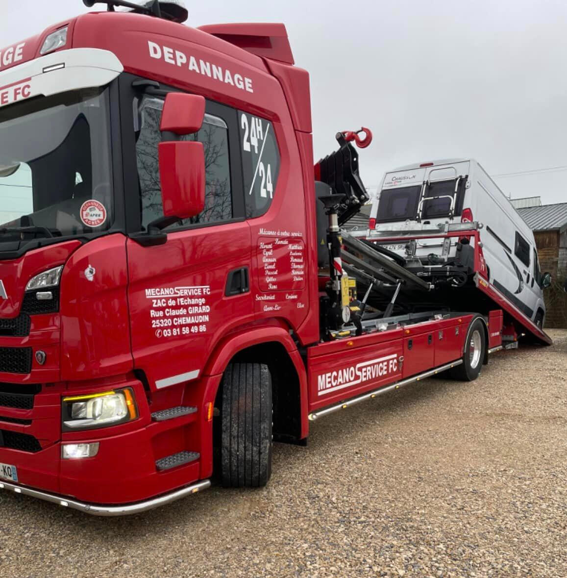 Dépanneuse rouge Mecano Service FC transportant camping-car blanc sur plateau hydraulique Doubs