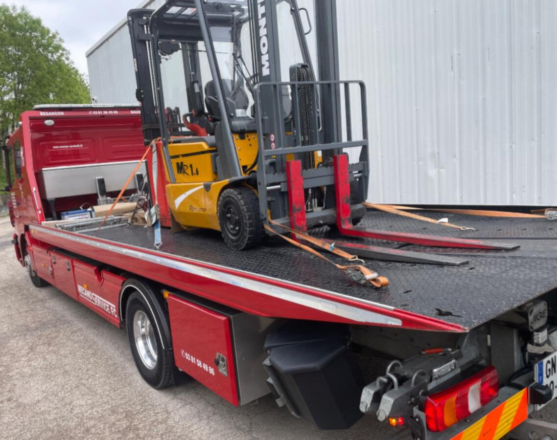 Une dépanneuse plateau Mecano Service F.C qui remorque un manitou jaune zone industrielle de Besançon